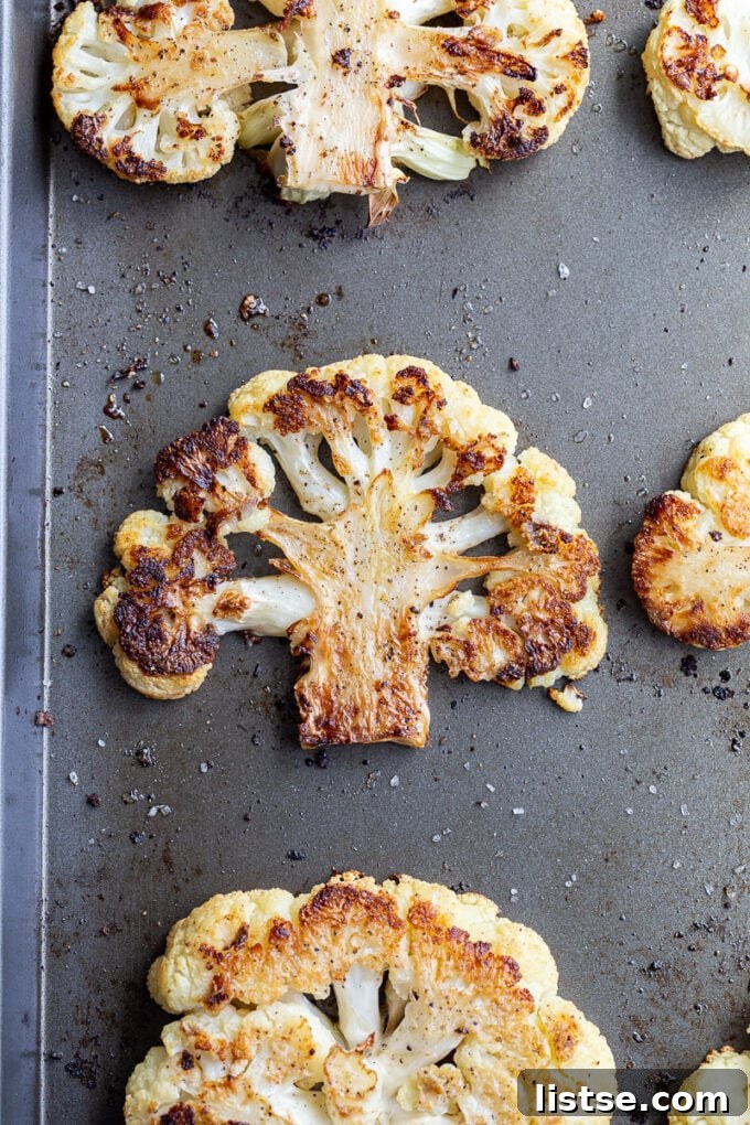 Savory Cauliflower Cutlets 4 Roasted cauliflower florets and steaks cooling on a baking sheet, displaying a beautiful golden-brown color and tender texture.