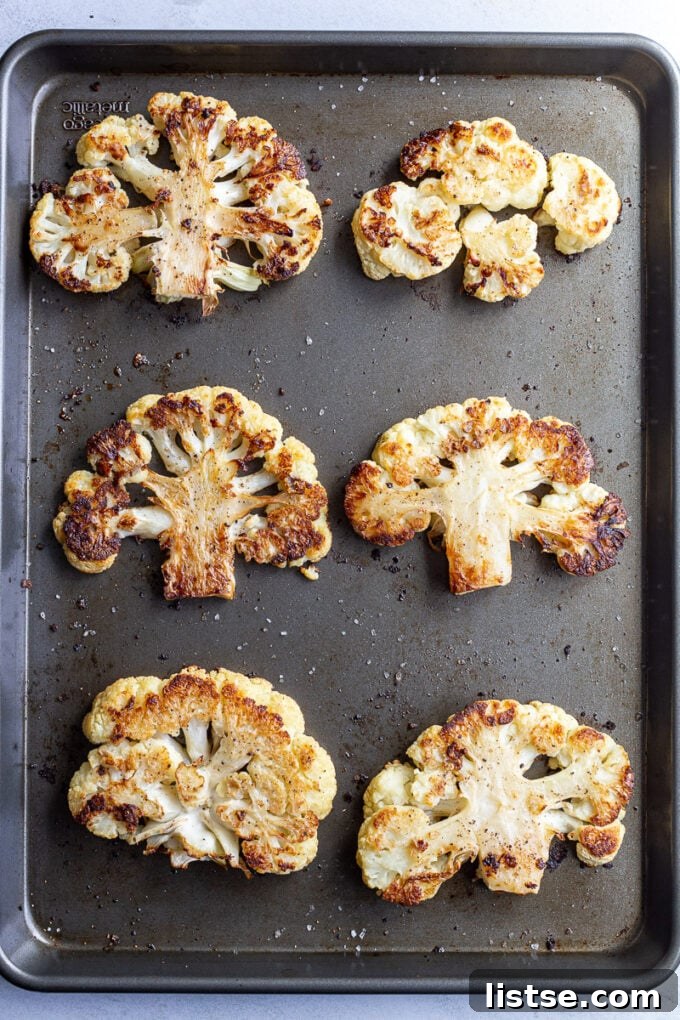 Savory Cauliflower Cutlets 5 Close-up view of roasted cauliflower pieces on a dark baking pan, showing caramelized edges and a soft interior.