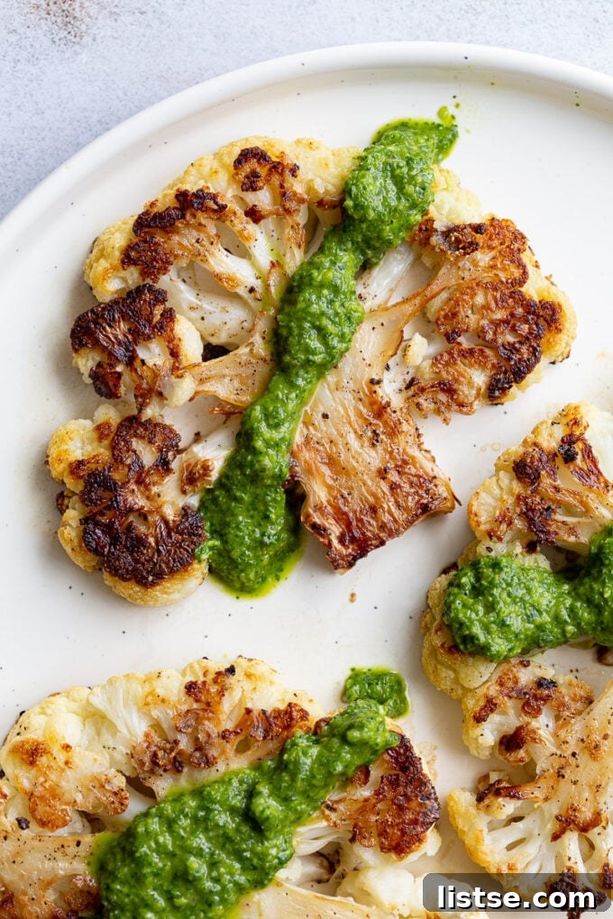 Savory Cauliflower Cutlets 6 A single perfectly roasted cauliflower steak on a rustic wooden board, generously topped with a vibrant green herb sauce.