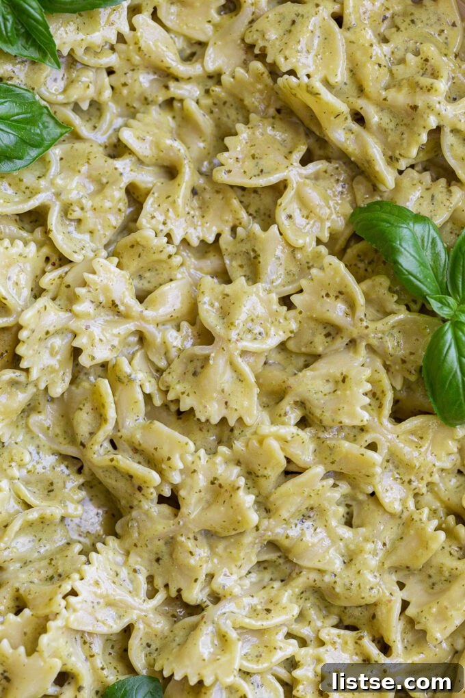 Close-up of bowtie pasta (farfalle) sumptuously covered in a rich pesto cream sauce.