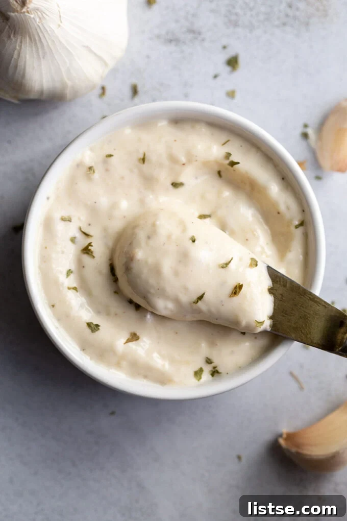 Golden Roasted Garlic Aioli 2 Spooning out Roasted Garlic Aioli from a small bowl.