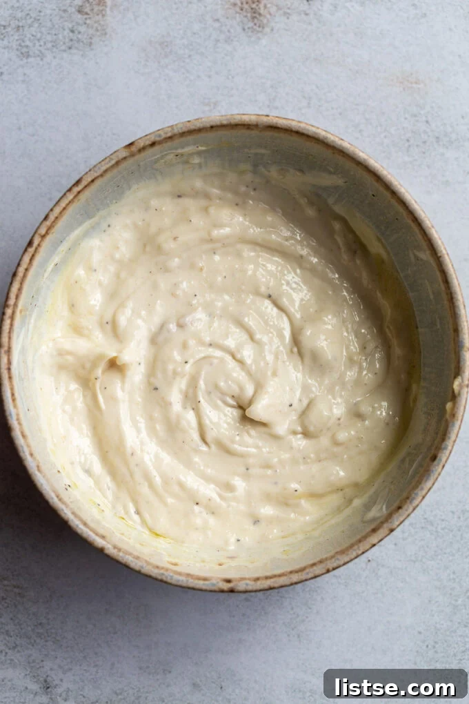 Golden Roasted Garlic Aioli 3 Making garlic aioli in a medium bowl.