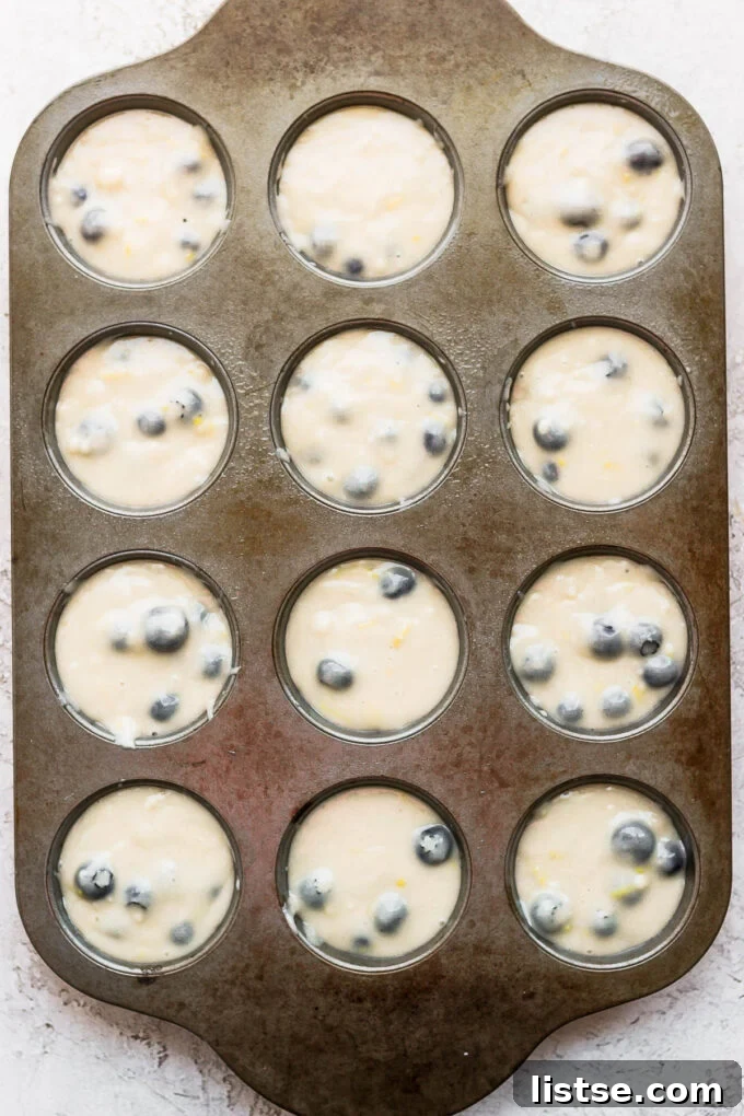 Muffin batter carefully scooped into a prepared muffin pan, showing the even distribution before baking.