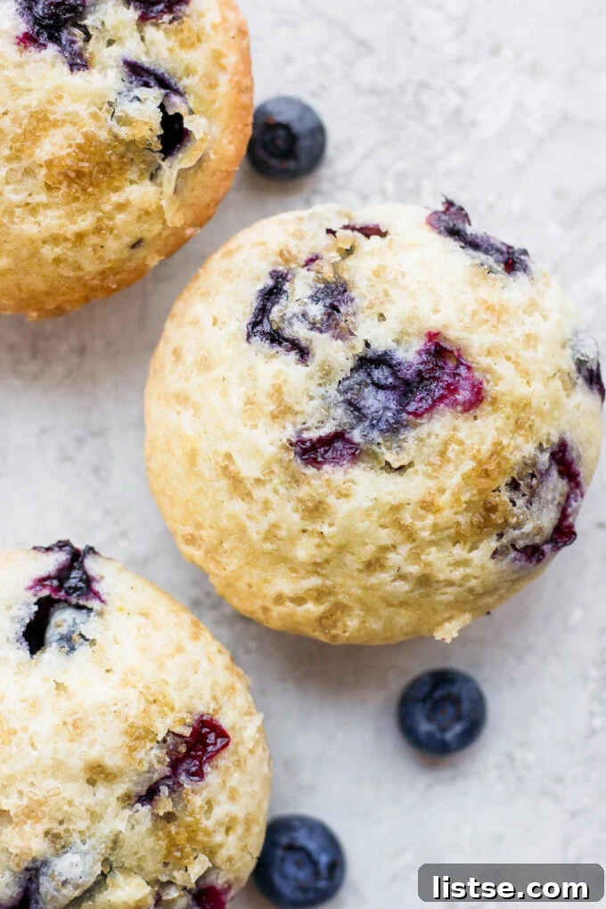 A close-up shot of the golden, crinkly top of a baked Vegan Blueberry Muffin, showing the raw sugar sprinkle.