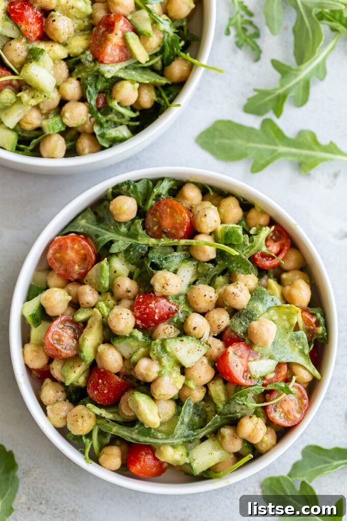 A serving of Chickpea Avocado Salad with fresh arugula in a white bowl, ready to be enjoyed.