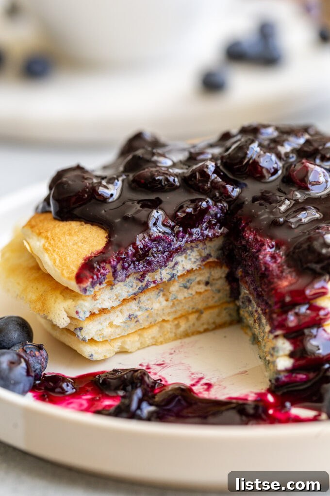 Sweet Blueberry Nectar 6 Rich blueberry syrup generously poured over a stack of fluffy pancakes, creating a mouth-watering visual.