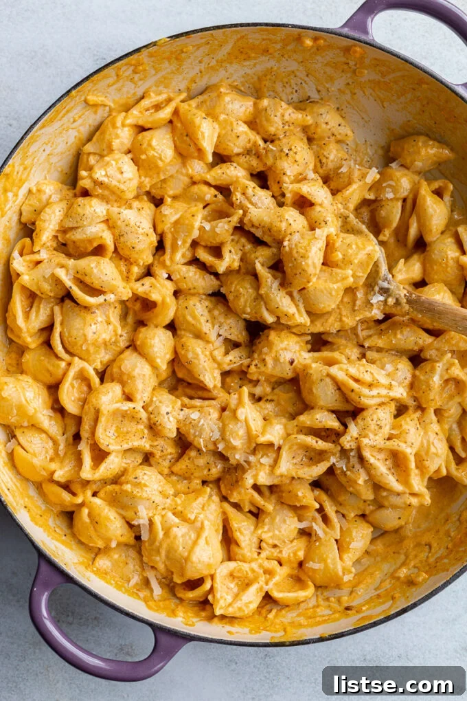 Creamy pumpkin macaroni pasta served in a large, rustic purple skillet, highlighting its vibrant color and inviting texture.