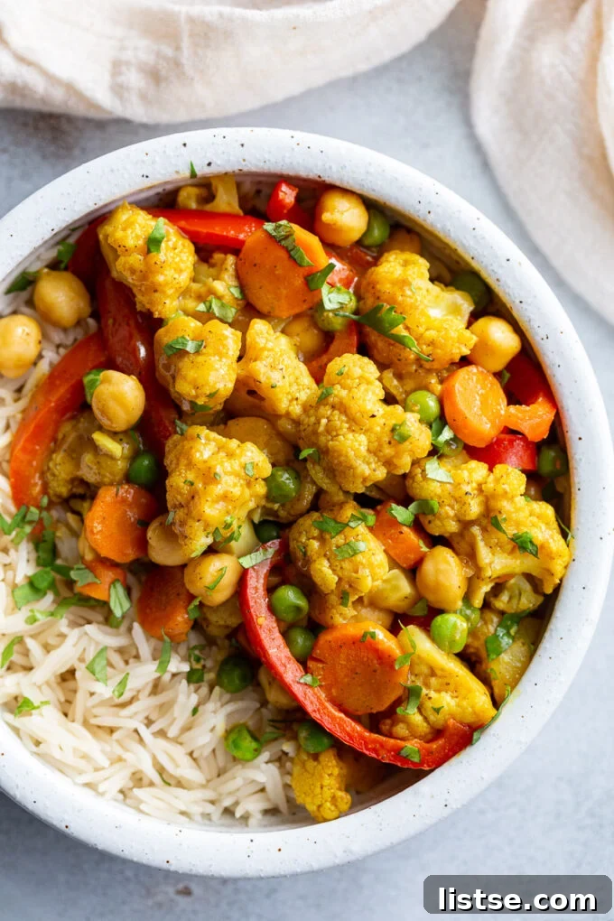 Cauliflower curry served over rice in a white bowl, garnished with fresh cilantro.