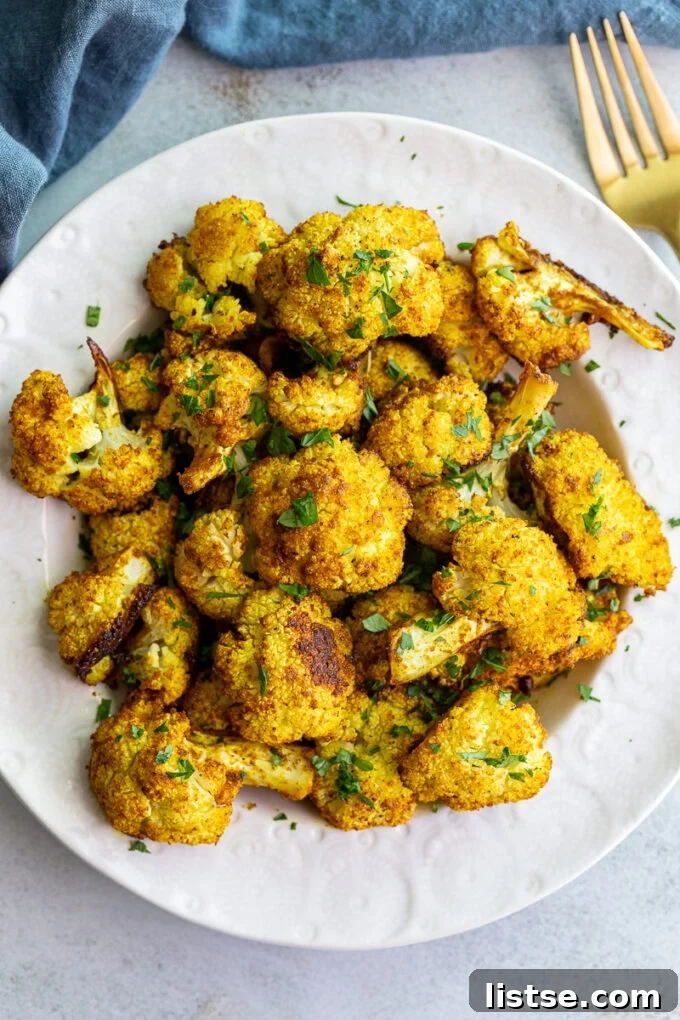 Curried cauliflower served in a white bowl, garnished with fresh herbs.