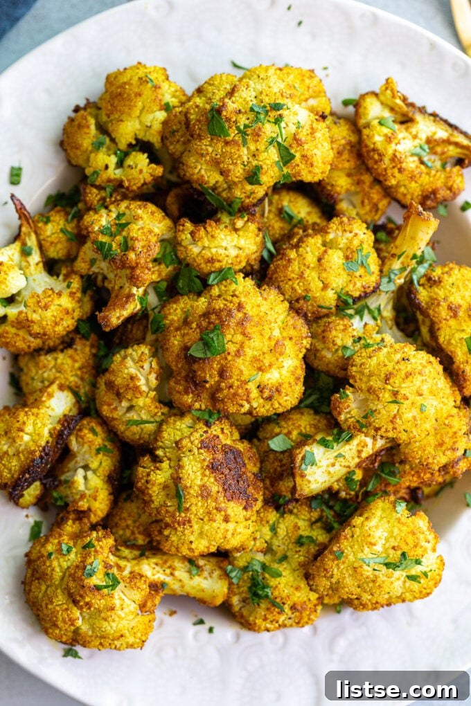 Cauliflower roasted with curry and garnished with fresh cilantro in a serving dish.