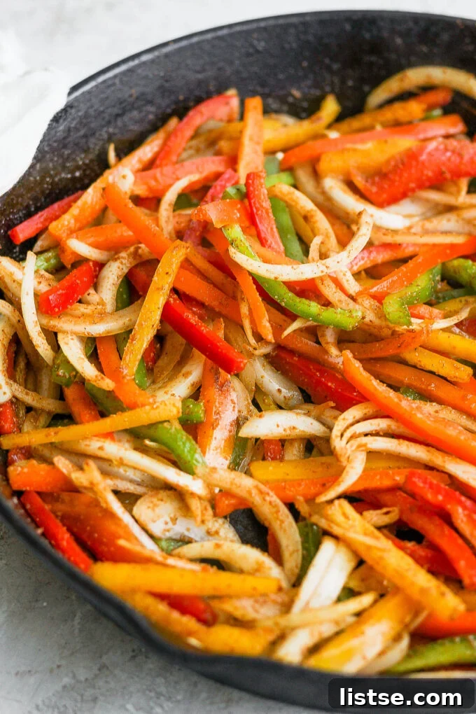 Fajita veggies cooking in a cast iron skillet.