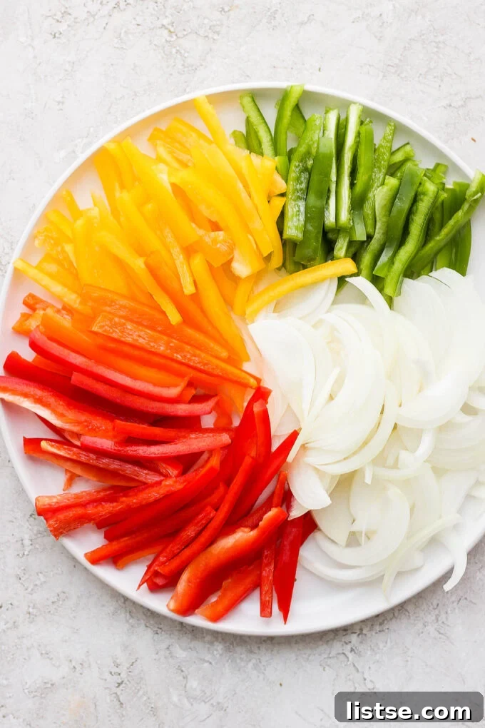 Colorful sliced bell peppers and onion on a white plate.