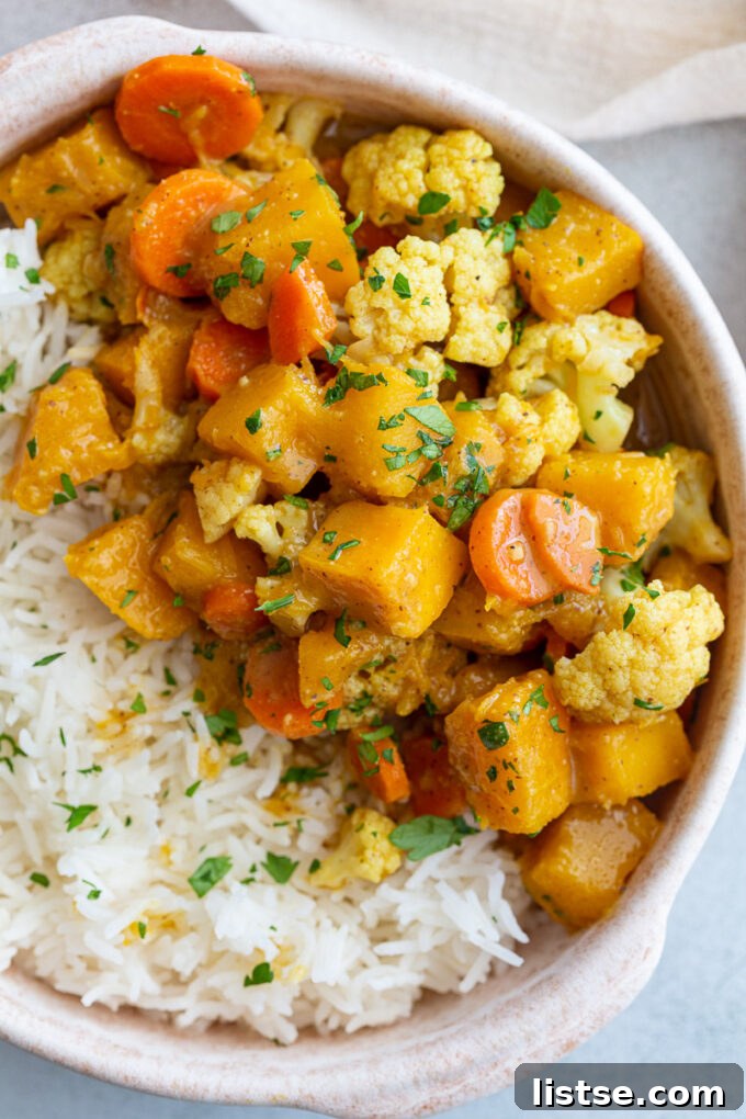 A bowl of vegan pumpkin curry served with rice, showing a generous portion ready for a satisfying meal.
