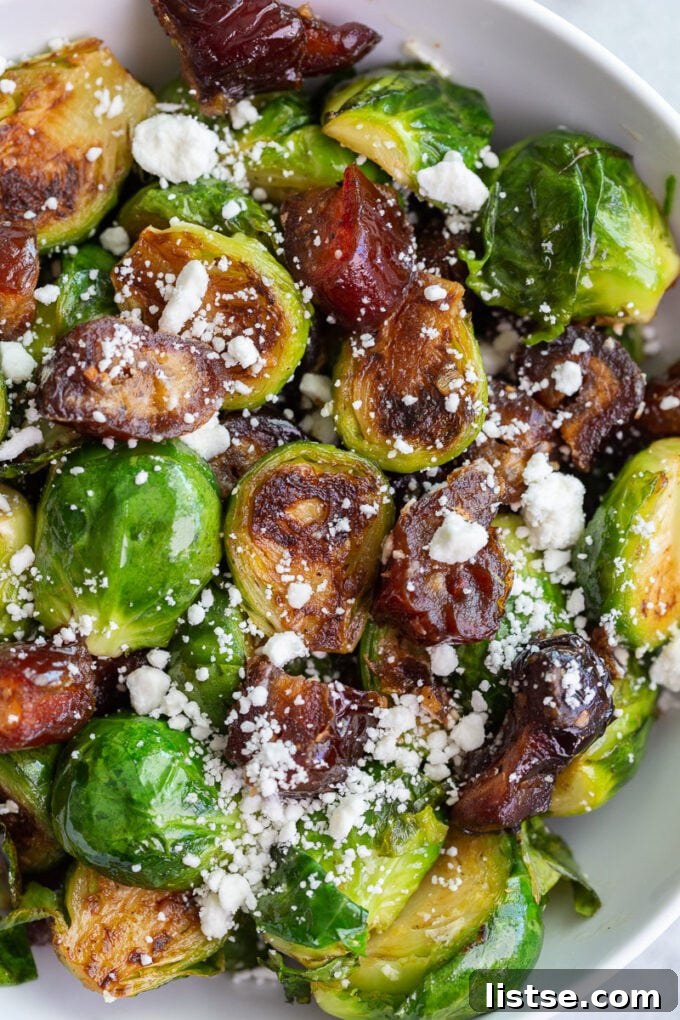 A freshly prepared bowl of Date Sweetened Brussels Sprouts, ready to be served, garnished with goat cheese.