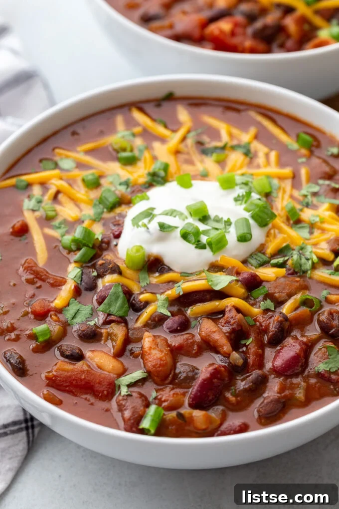 Ultimate Instant Pot Chili 5 Chili in a bowl topped with sour cream, green onions and cheese.
