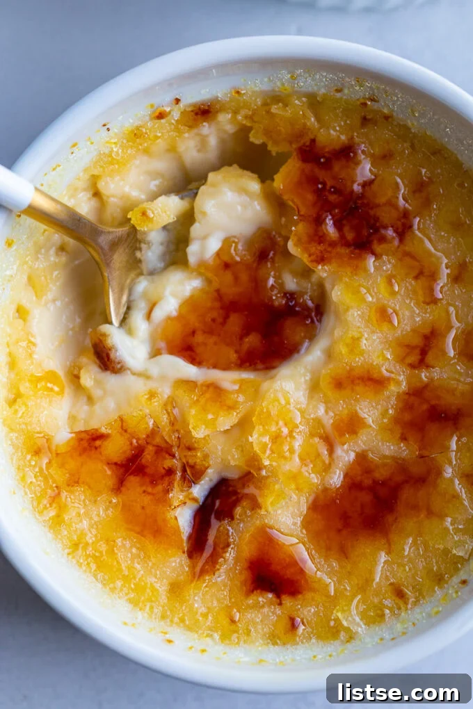 A spoon in a small bowl with Crème Brûlée, showing the crisp top and creamy interior.