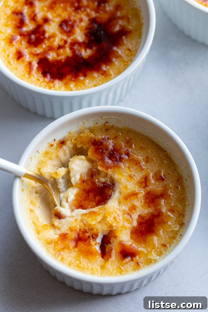 Spooning out a bite of Creme Brulee from a white ramekin, showing the perfect texture.