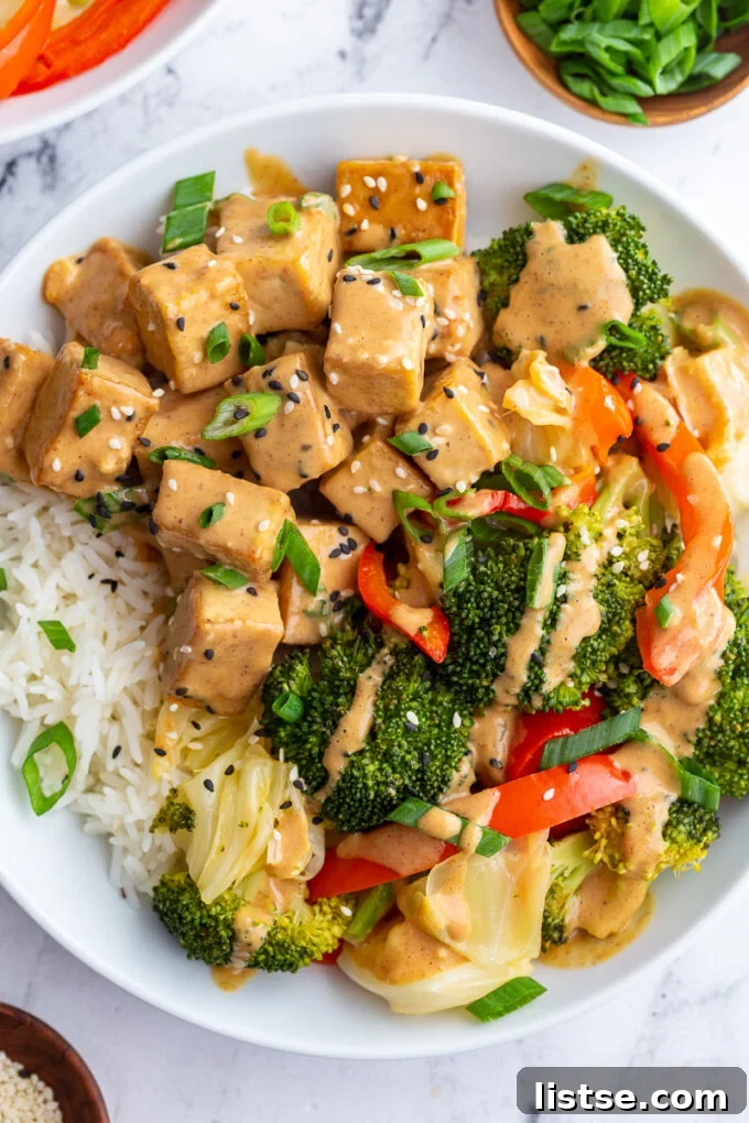 Golden seared tofu and vibrant broccoli drenched in creamy peanut sauce, served over a bed of fluffy white rice.