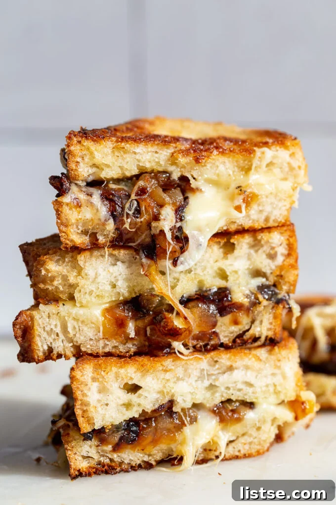 Caramelized Onion grilled cheese stacked on top of itself with cheese and onion oozing out