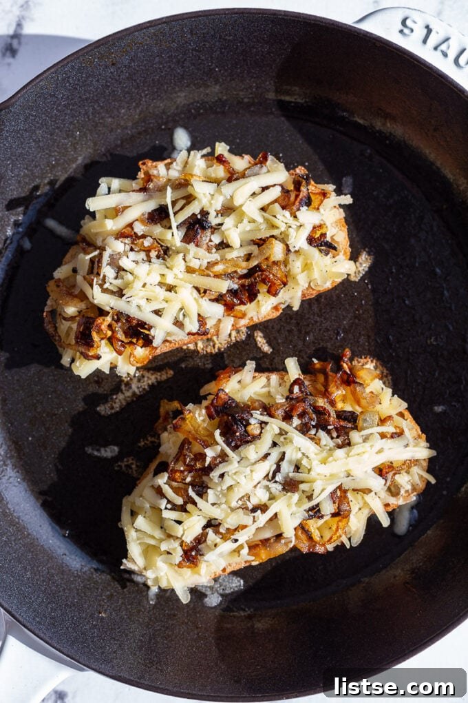 Caramelized onion grilled cheese being cooked in a cast iron skillet on a stovetop