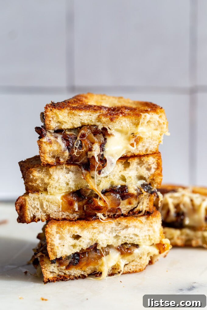 Two halves of a Caramelized Onion grilled cheese sandwich stacked, showing the melted cheese and onions