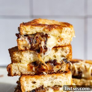 Caramelized Onion grilled cheese stacked on top of itself with cheese and onion oozing out