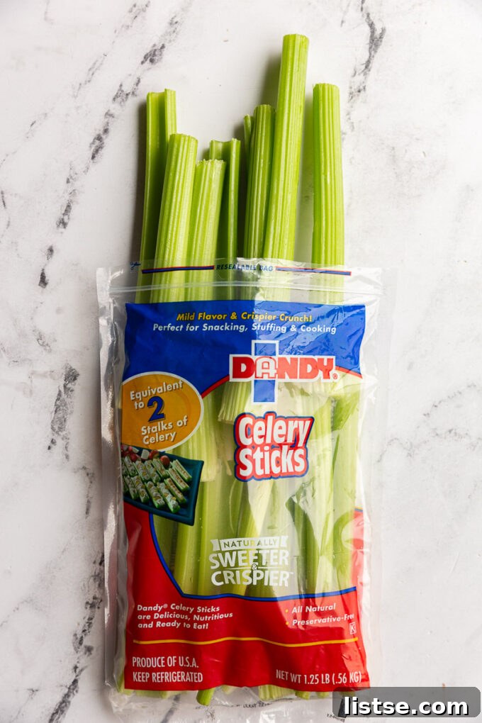 Variety of fresh fruits and vegetables, including celery, apples, and limes, arranged for juicing.