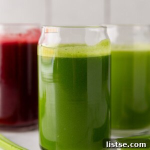 A glass of colorful beet celery juice, garnished with a celery stick and lime.