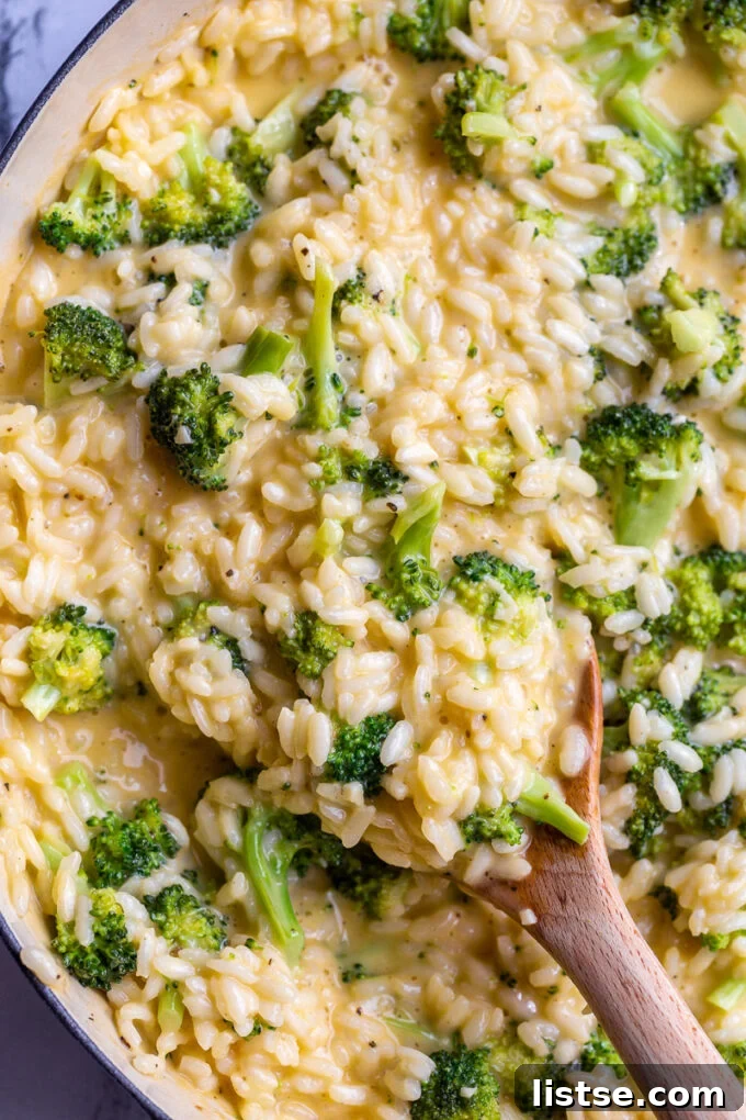 Creamy Broccoli Cheese Risotto 3 A wooden spoon stirring creamy risotto in a large pot, showing the process of cooking.