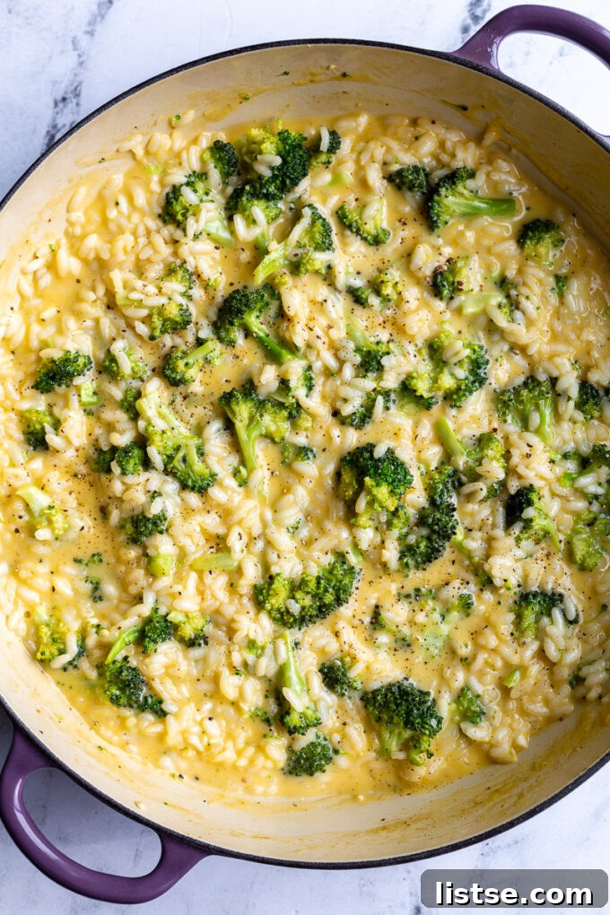 Creamy Broccoli Cheese Risotto 4 Close-up of creamy cheesy broccoli risotto being cooked in a large pot, with steam rising.
