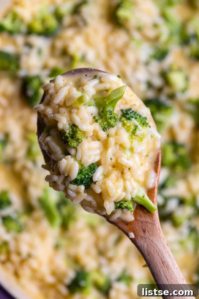 Creamy Broccoli Cheese Risotto 5 A wooden spoonful of creamy cheesy risotto, highlighting the texture and ingredients.