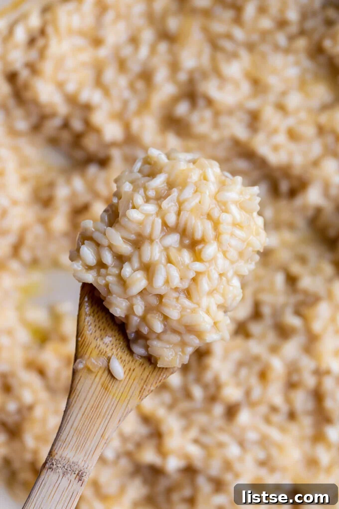 Crafting Perfect Risotto 3 A wooden spoon lifting a scoop of creamy risotto from a bowl.
