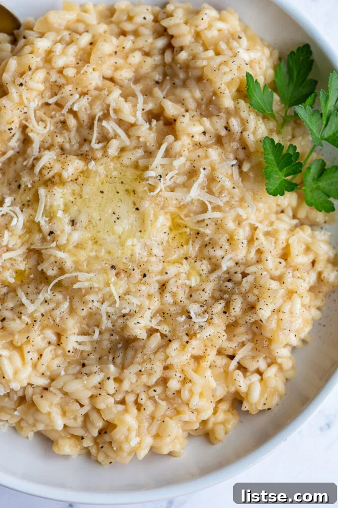 Crafting Perfect Risotto 9 A bowl of creamy risotto, elegantly topped with a dollop of butter and a sprinkle of grated Parmesan cheese.
