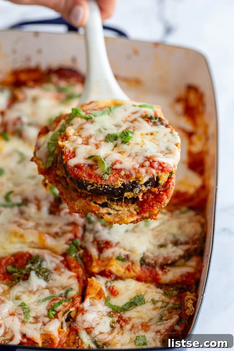 Hearty Eggplant Parmesan Bake 2 Serving a portion of eggplant parmesan out of a white baking dish.