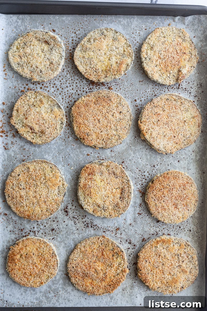 Hearty Eggplant Parmesan Bake 5 Breaded eggplant slices on a sheet pan.
