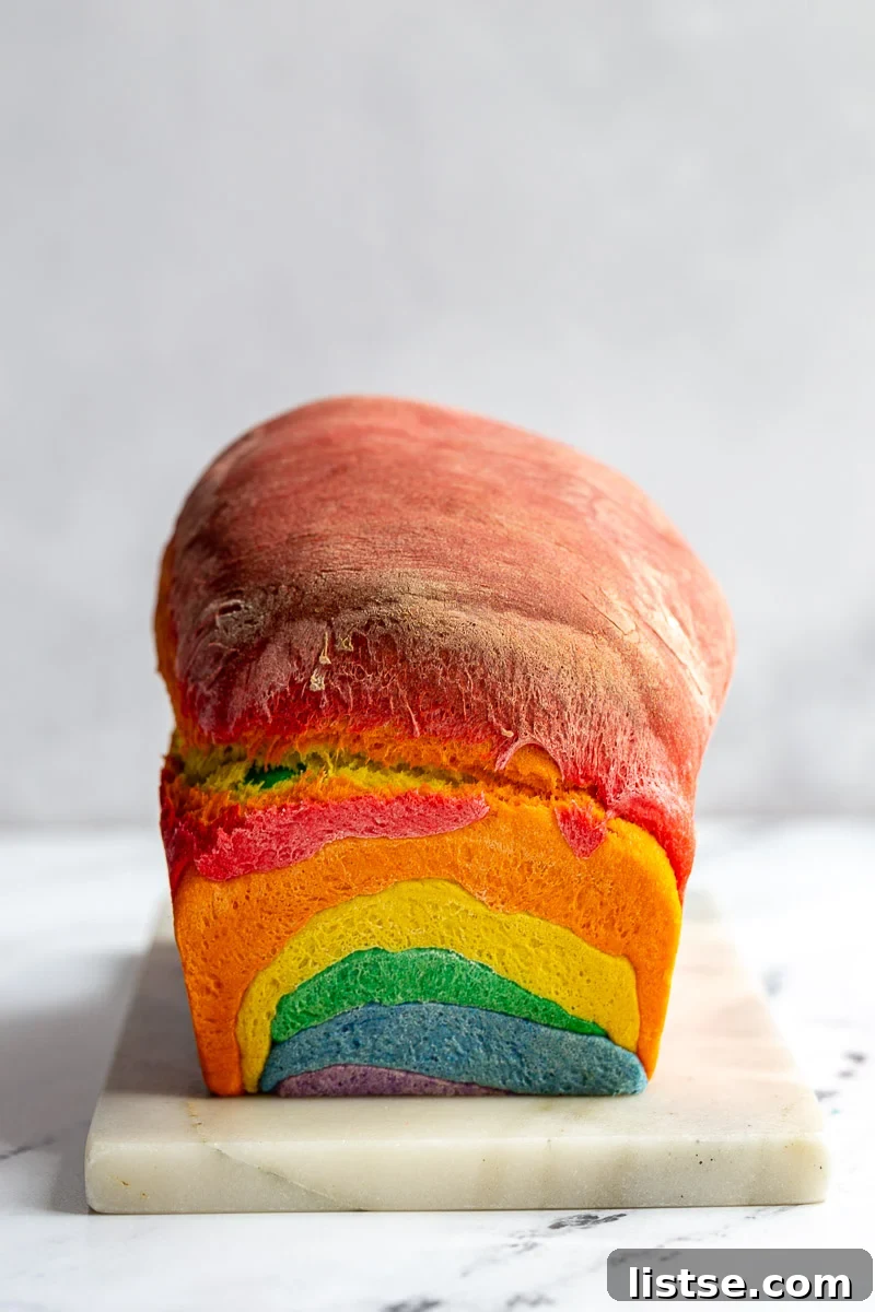 Kaleidoscope Loaf 4 A whole loaf of un-sliced rainbow bread, golden brown on top, ready to be enjoyed.