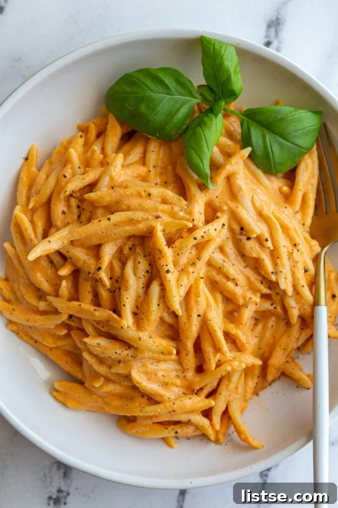 Creamy Roasted Red Pepper Tofu Pasta 2 A vibrant bowl of roasted red pepper tofu pasta garnished with fresh basil.