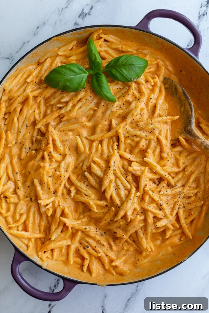 Creamy Roasted Red Pepper Tofu Pasta 3 Spiral pasta coated in a rich, red pepper sauce in a large skillet, ready to serve.