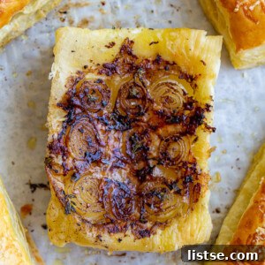 Individual French Onion Tarts arranged neatly on a baking tray, showing the crisp pastry and rich filling.