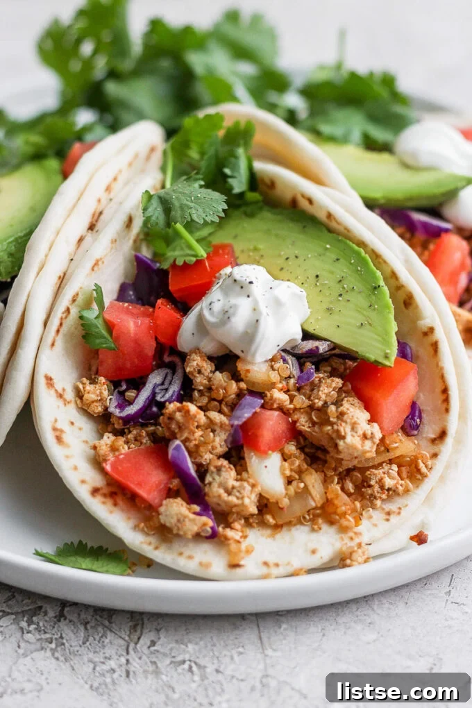 Zesty Quinoa Tofu Taco Crumbles 2 A perfectly prepared soft tortilla, generously filled with savory vegan quinoa tofu taco meat and topped with a colorful array of fresh, crisp vegetables like lettuce, tomatoes, and cilantro, ready to be enjoyed.