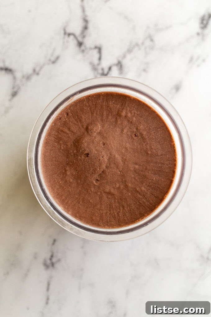Unprocessed chocolate ice cream base frozen solid in a Ninja Creami pint, ready for churning.