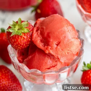 Strawberry sorbet in an ice cream dish with strawberries around the scene