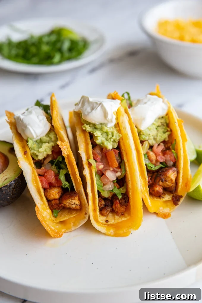 3 cheesy stuffed tacos topped with guacamole and sour cream on a plate