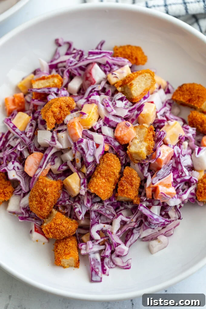 Close-up of a colorful purple cabbage salad topped with perfectly diced buffalo wings, showcasing its appealing textures and ingredients.