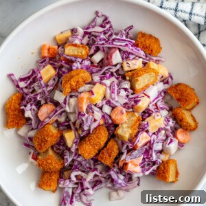 Two wide bowls of cabbage and carrot salad, lavishly topped with diced buffalo wings, invitingly displayed.