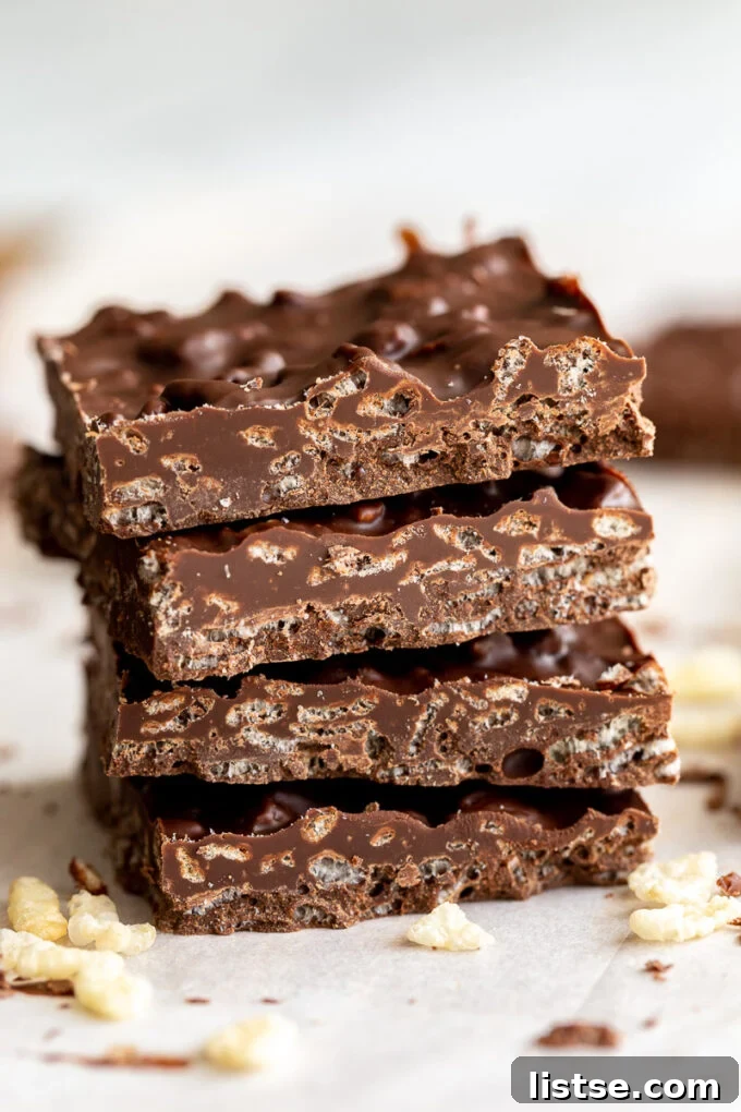 Four decadent homemade crunch bars stacked neatly, showcasing their rich chocolate and crispy rice cereal texture.