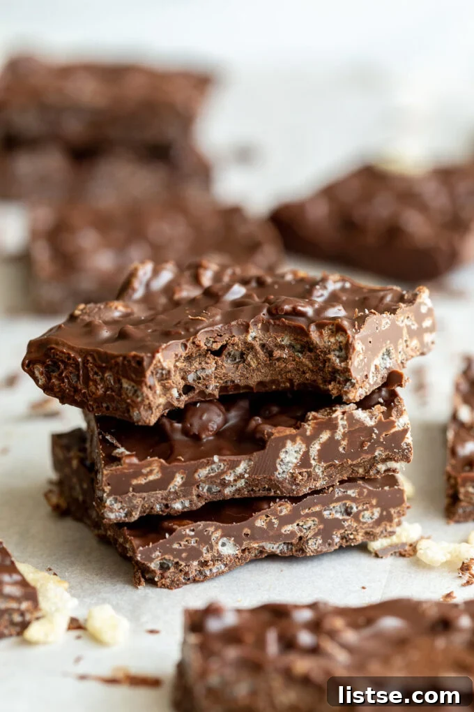 Three decadent homemade crunch bars stacked, with one having a bite taken out, revealing the crispy interior.