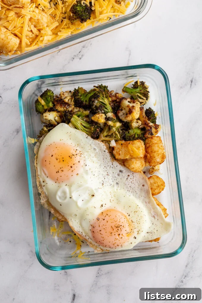 Plant-Powered Breakfast Prep 4 Three meal prep containers filled with roasted vegetables, tater tots, and cheese, ready for storage.