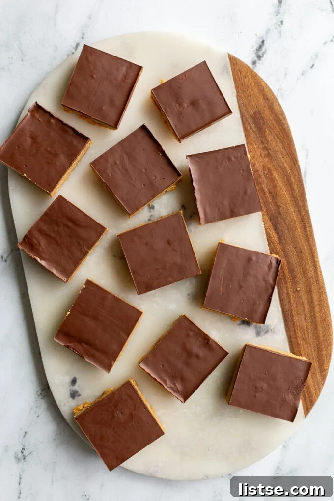 Mouth-watering chocolate peanut butter bars arranged elegantly on a marble cutting board, glistening and ready to be served.
