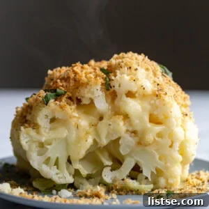 A close-up of a generously stuffed whole baked cauliflower, oozing with cheese and topped with crunchy breadcrumbs, ready to be served.